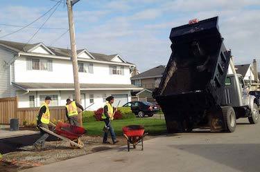 Construction team greets asphalt truck with wheelbarrows