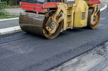 Asphalt roller compacts new pathway