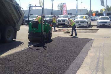 Three asphalt professionals repairing surface