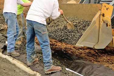 Drainage team shovels gravel into trench