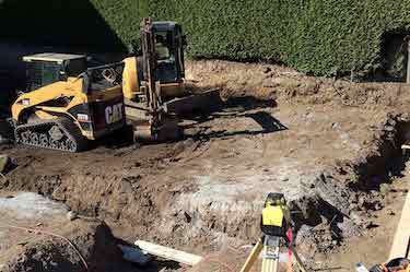 Bobcat and excavator prepare construction site foundation
