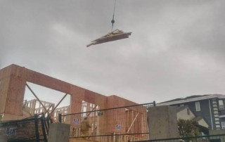Crane delivers engineered trusses to framing crew on construction site